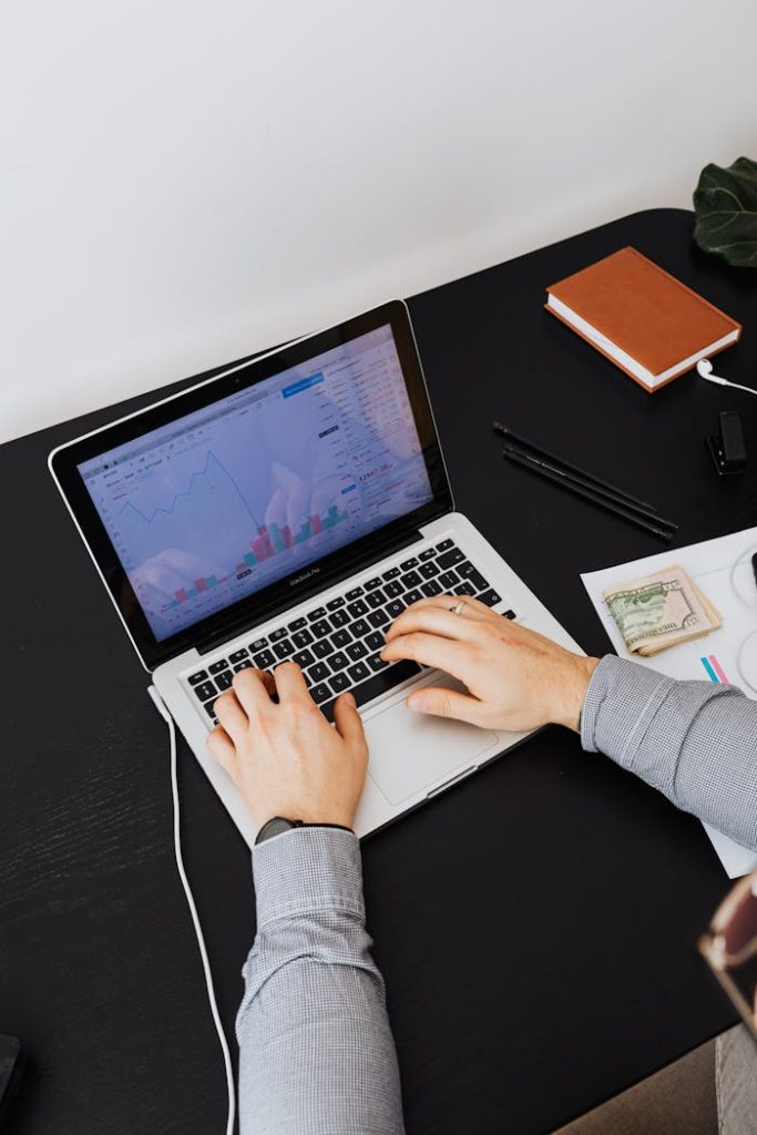 pexels photo 5717762 Hands typing on a laptop showing graphs on screen, analyzing financial data.